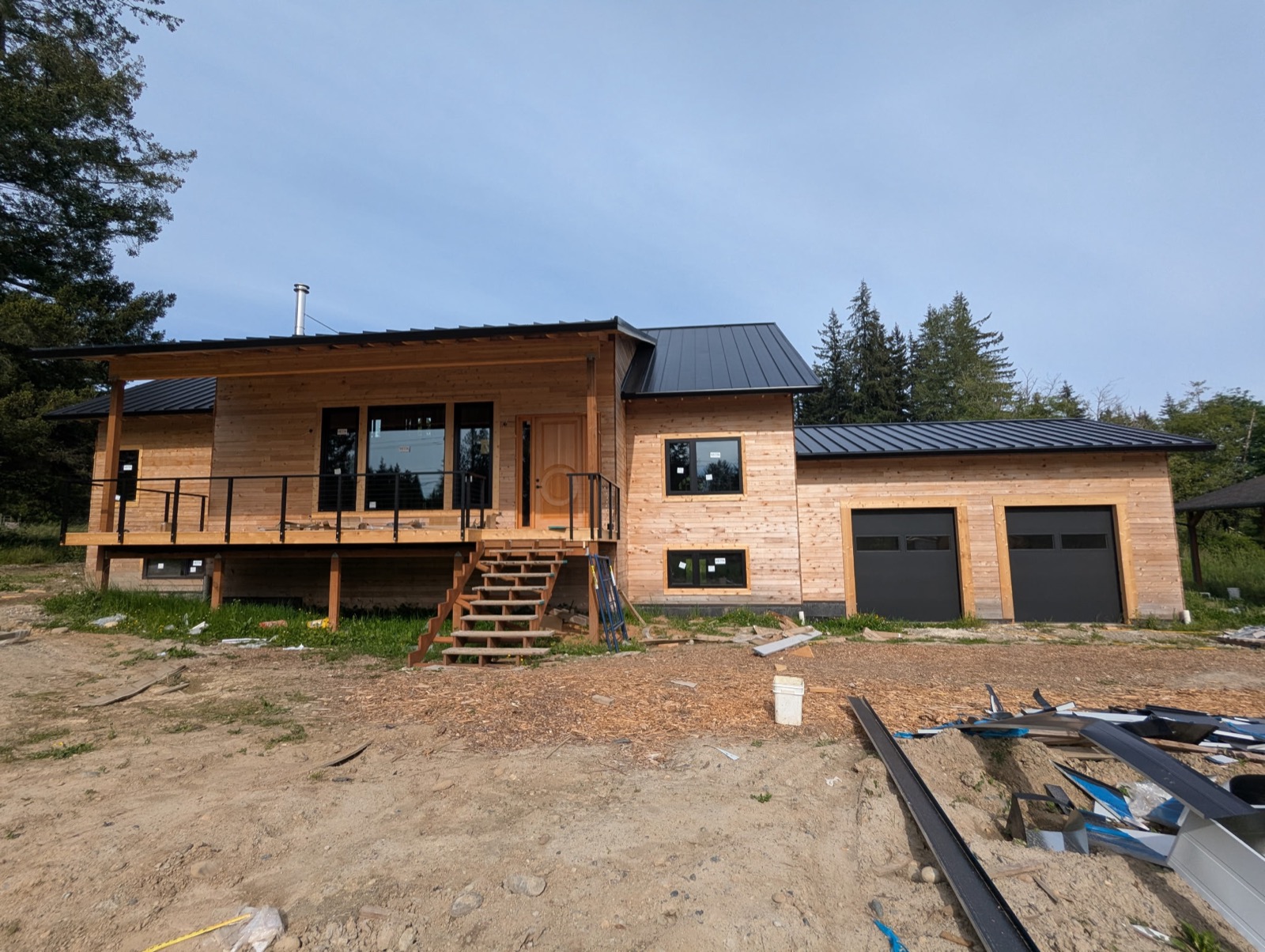 Standing-seam metal roof installation on a home with cedar siding and covered deck